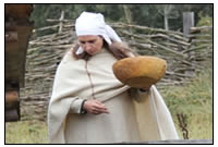 In einem Museumsdorf f&uumlttert eine Magd die Schweine mit K&uumlchenabf&aumlllen.