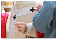 Beim Programmpunkt Kleidung des Bischofs hilft ein Diener dem Kirchenf&uumlrsten.